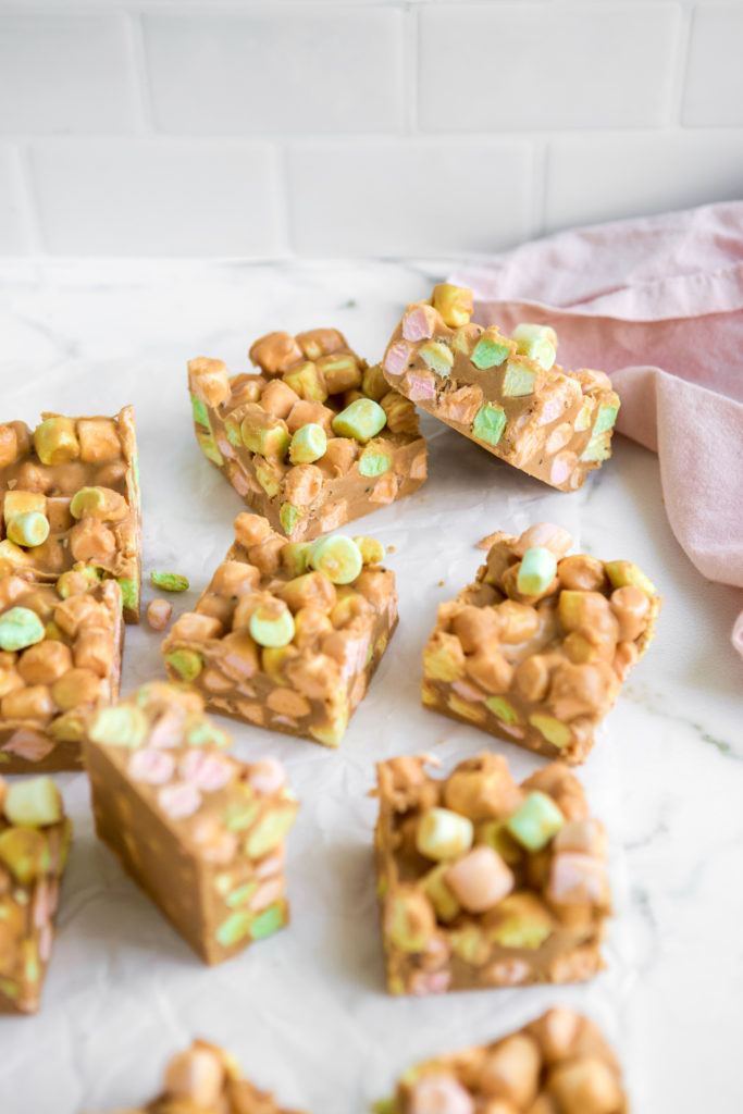Peanut butter confetti bars on parchment paper with pink napkin in background.