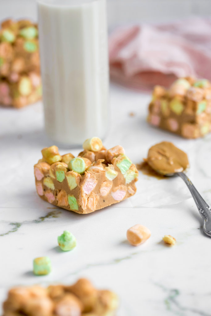 Side angle of a confetti squares with a spoonful of peanut butter right beside it.