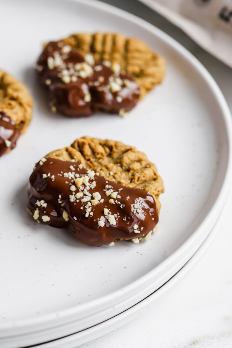 close up of chewy peanut butter cookies with chocolate and peanuts on a plate