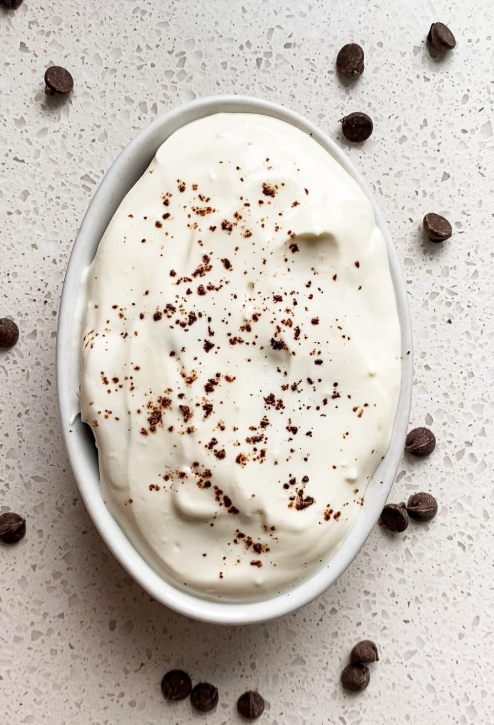 overhead shot of healthy chocolate zucchini baked oats with cream cheese frosting sprinkled with cocoa powder 