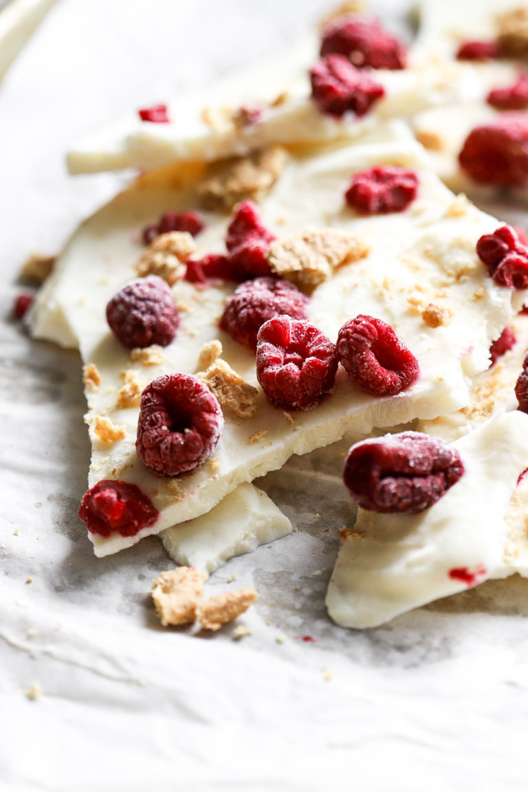 side shot of frozen greek yogurt bark with raspberries and graham wafers on parchment paper