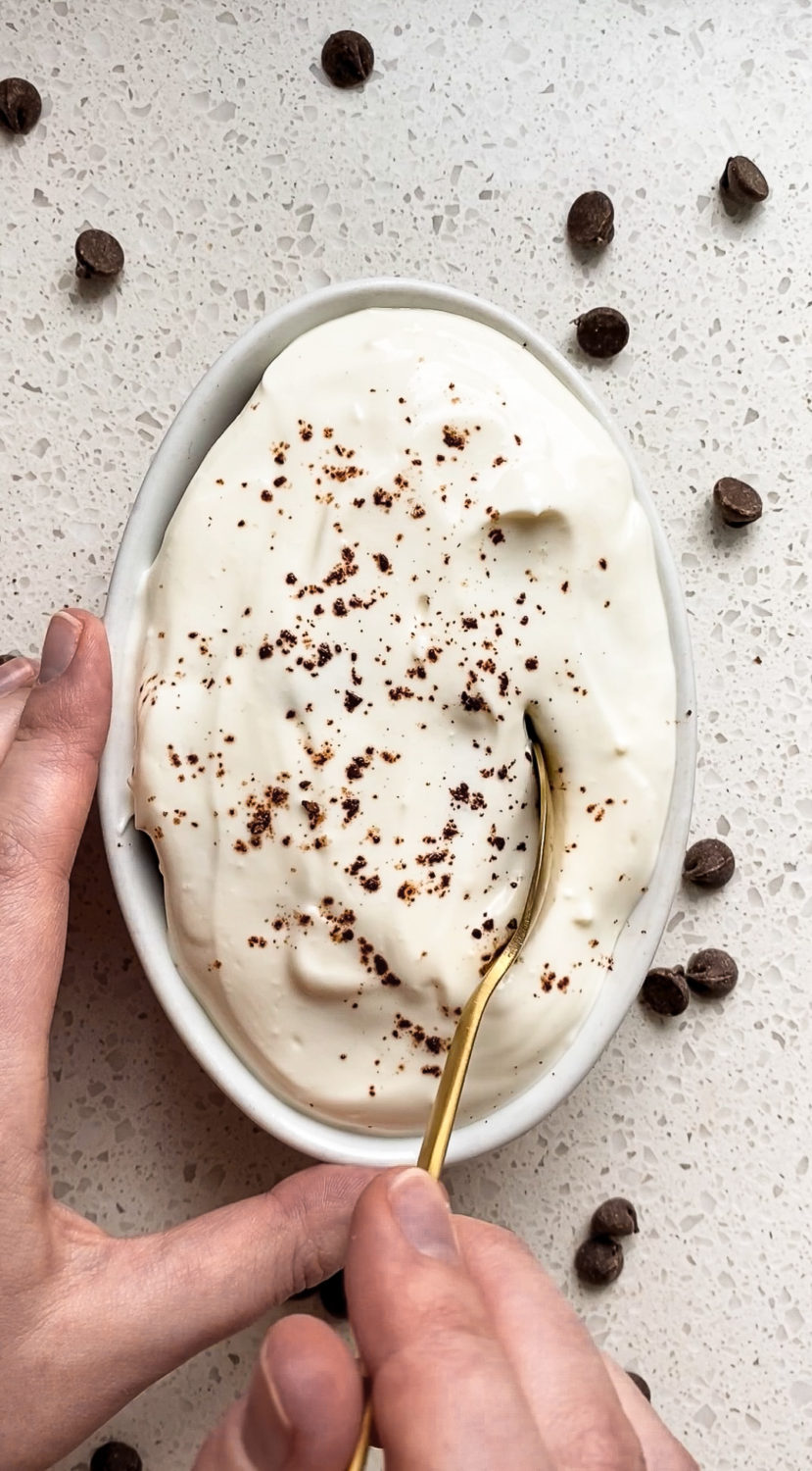 a spoon being inserted in a serving of baked chocolate zucchini oats with cream cheese frosting 
