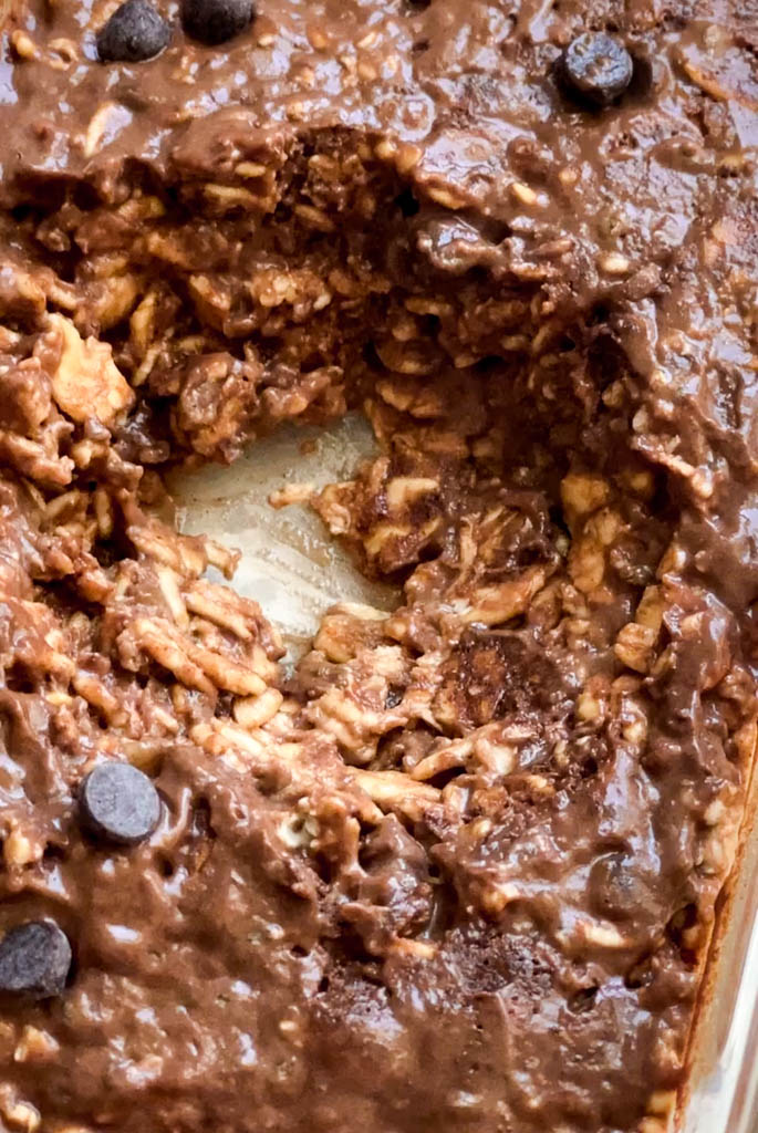 close-up of peanut butter chocolate overnight oats in a glass casserole with one spoonful missing 