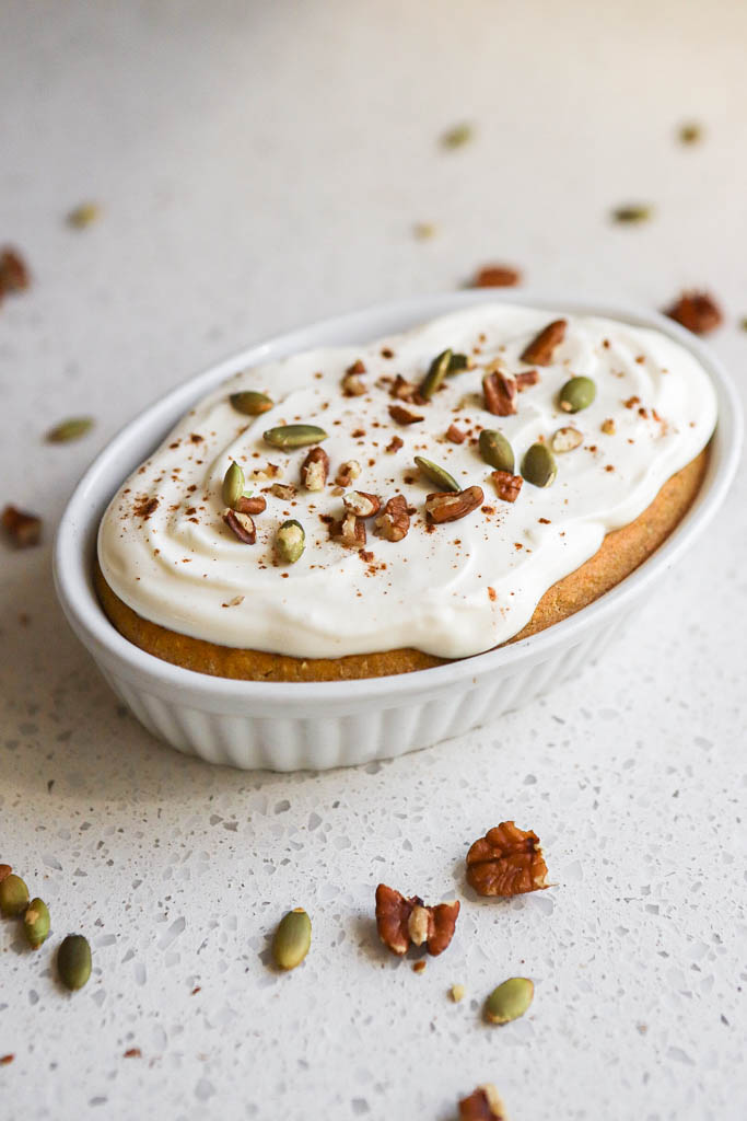 side view of a casserole dish with pumpkin baked oats topped with nuts and seeds 
