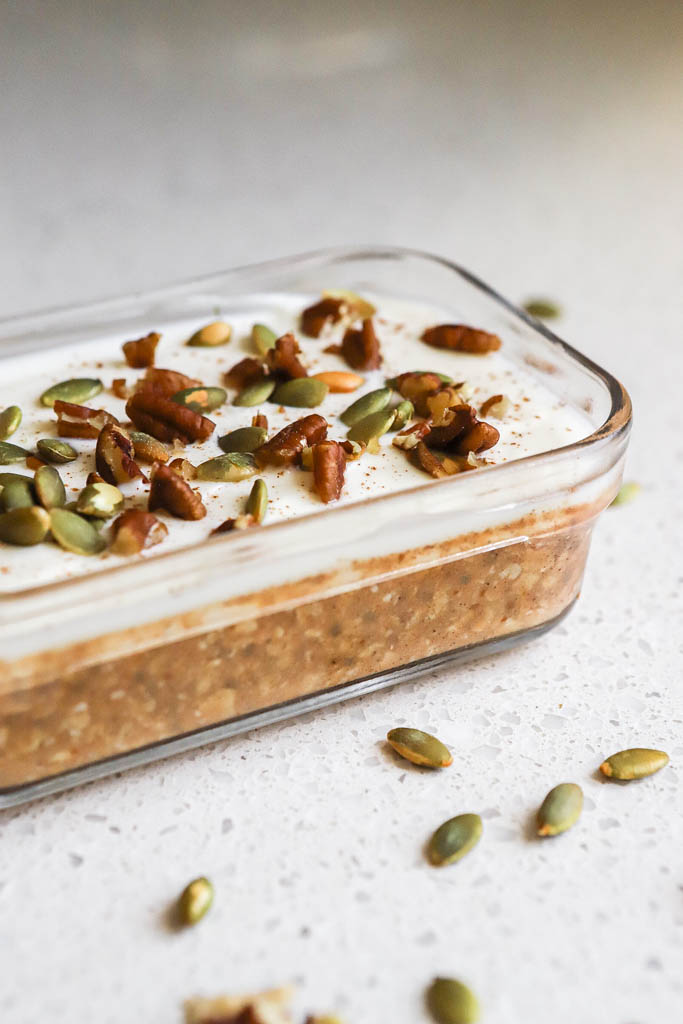 a small casserole dish with pumpkin pie overnight oats topped with nuts and seeds 