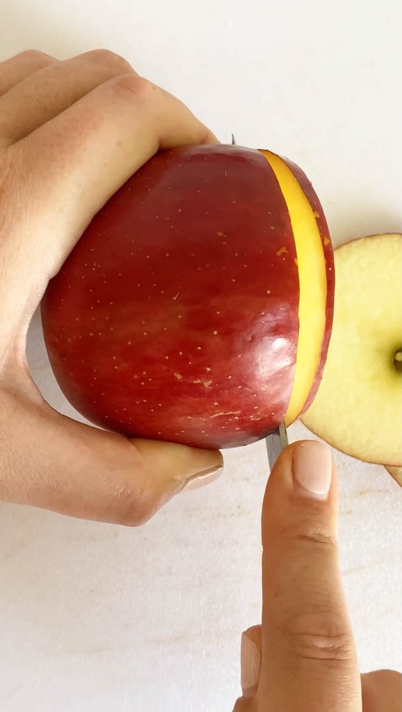 apple slices in air fryer being cut up with a knife