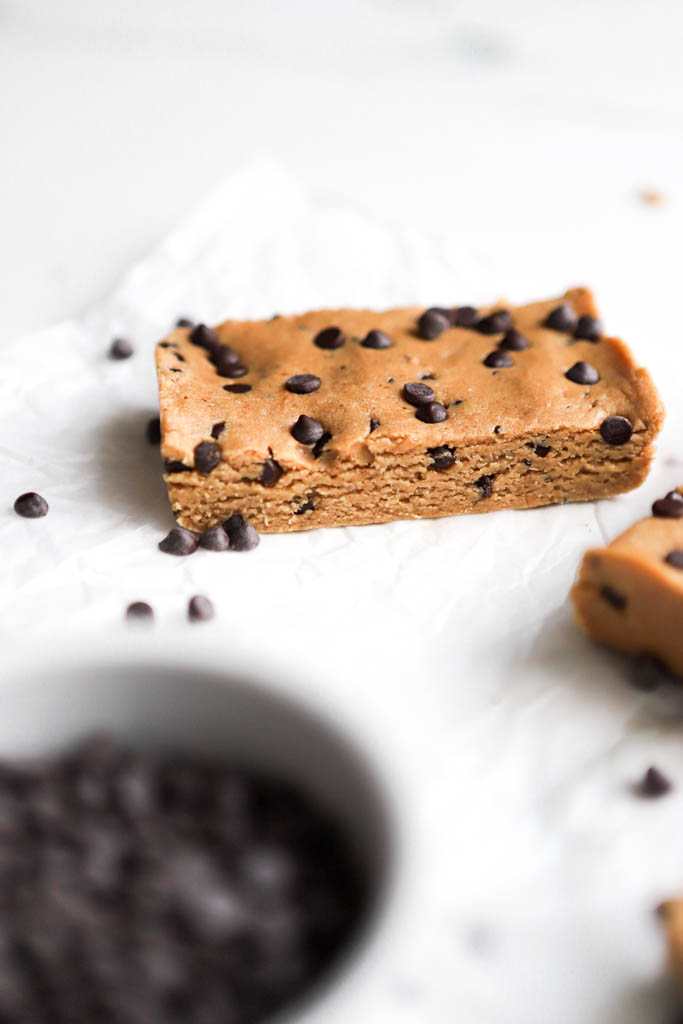 side view of protein perfect bar with a bowl of mini chocolate chips in the foreground