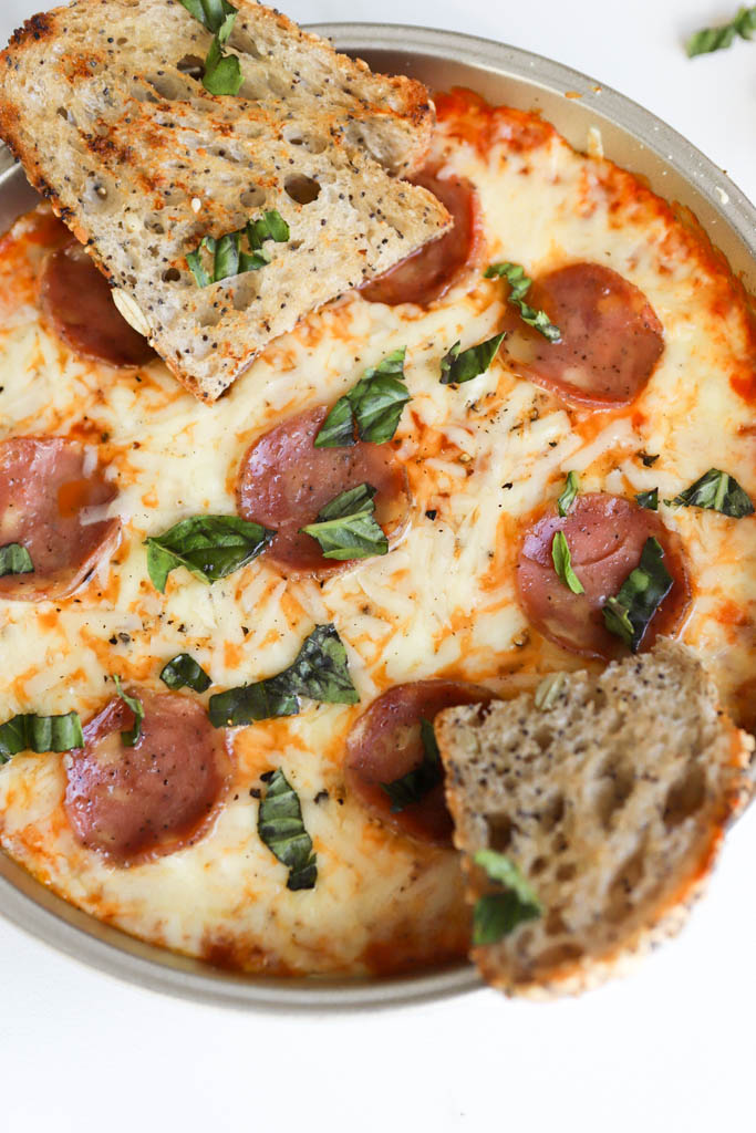 close up shot of cream cheese pizza dip with fresh chopped basil and garlic sourdough