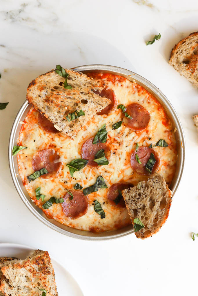 overhead shot of pepperoni pizza dip in a silver pan with sourdough slices