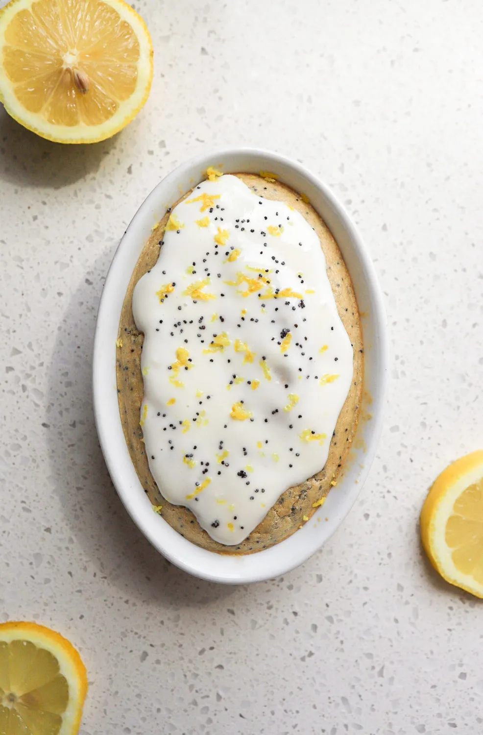 single serving lemon poppyseed baked oats with lemon zest on top and lemon wedges