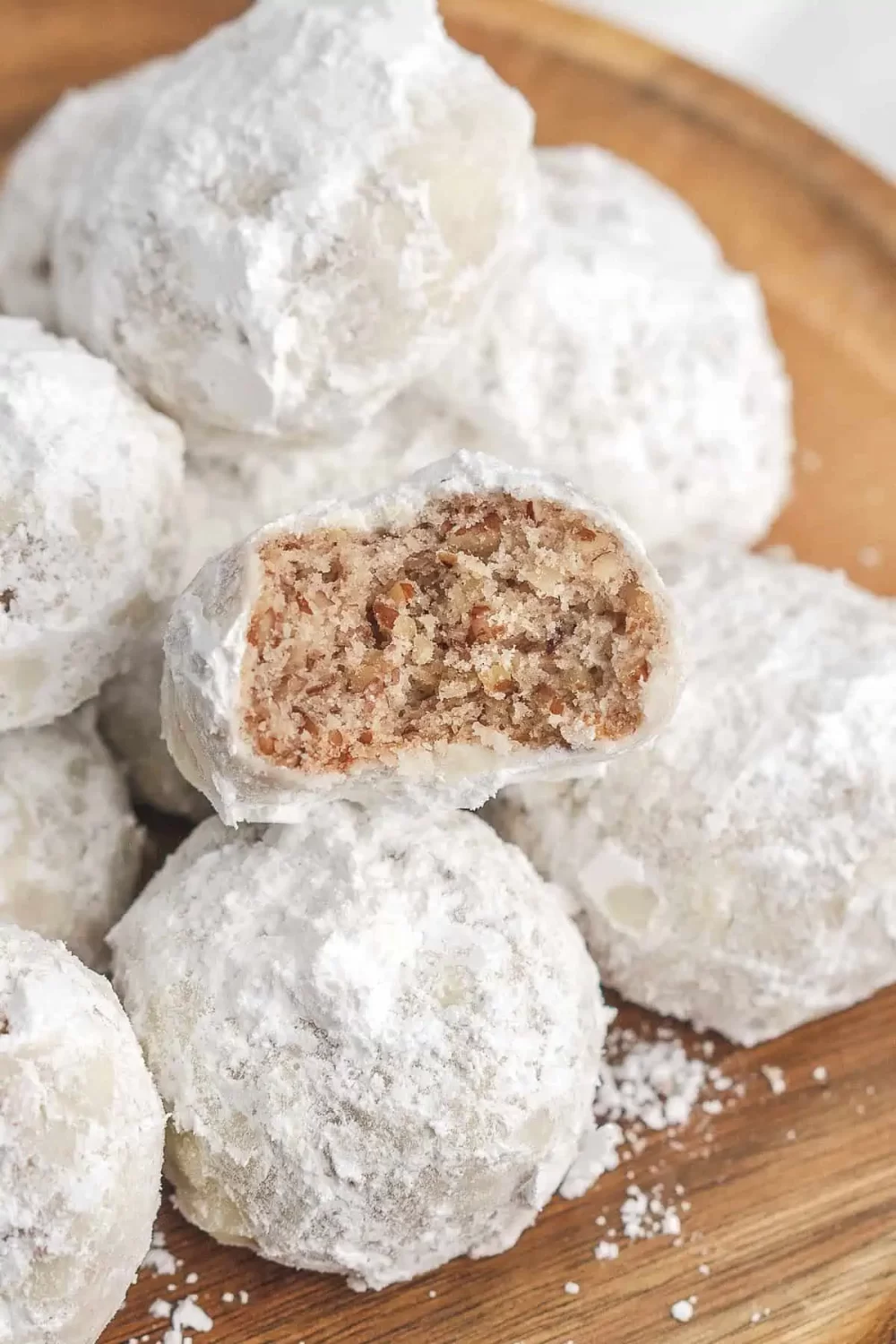 Close up shot of an easy christmas cookie recipe with powdered icing sugar on wooden plate.