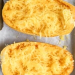 Cooked spaghetti squash strands being fluffed with a fork inside the shell