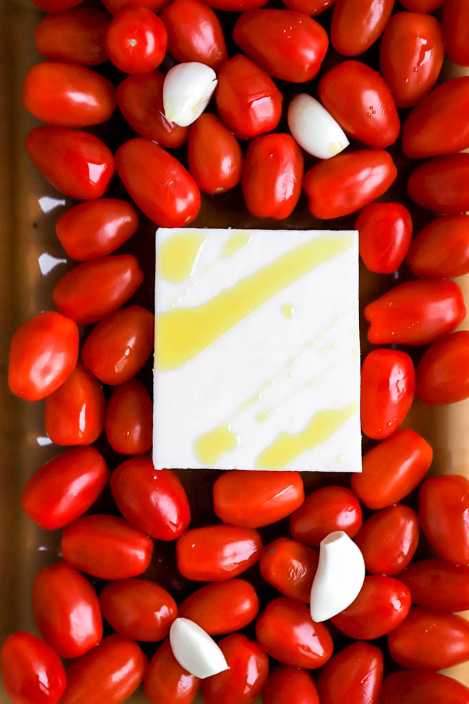 block of feta cheese with cherry tomatoes in casserole dish