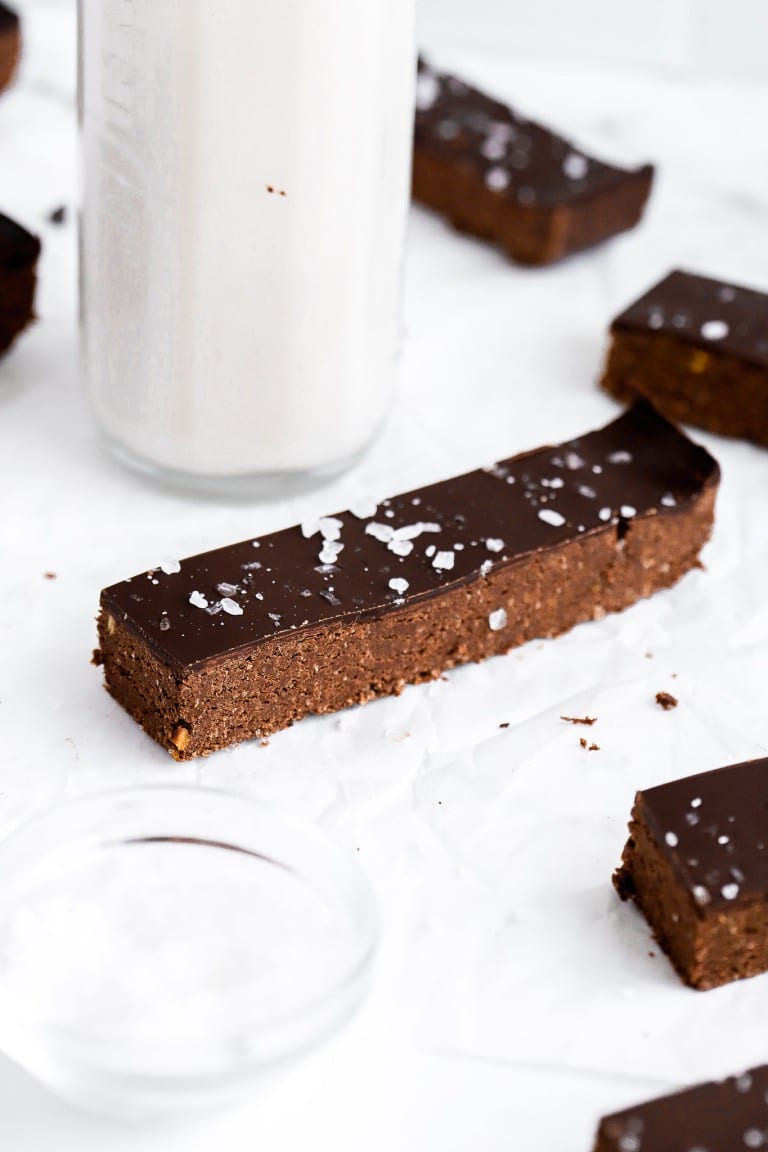 close up shot of chocolate peanut butter protein bar with flakey sea salt on top with glass of milk