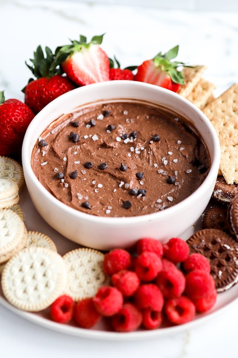 side angle of chocolate peanut butter dip in a pink bowl with fresh fruit