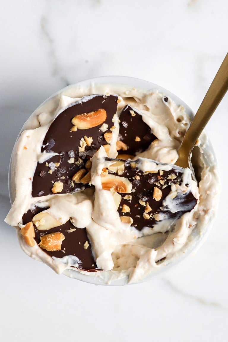 top down view of broken chocolate shell with dairy-free yogurt in white ramekin