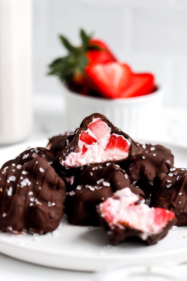 close up shot of melted chocolate yogurt mixture on white plate with fresh strawberries in the background