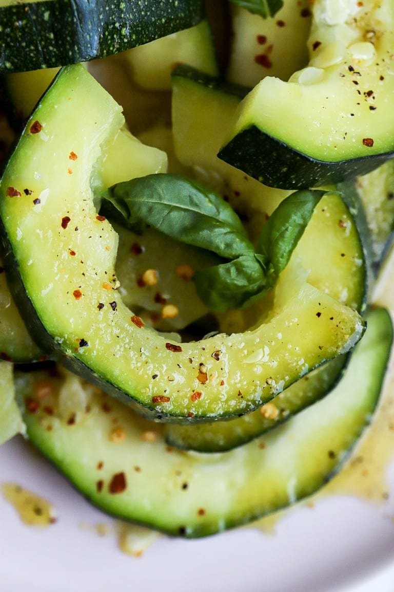 close up top down view of zooked zucchini with fresh basil and salt and black pepper