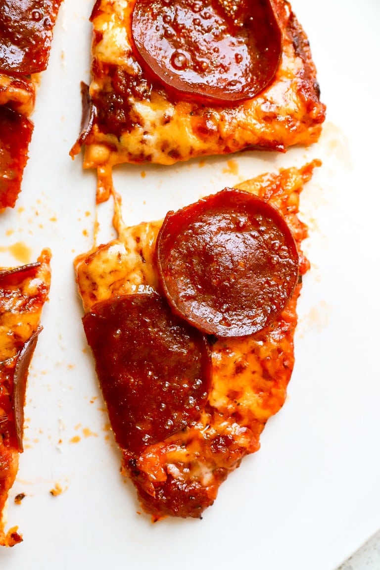 top down view of flour tortilla with pizza sauce and cheddar cheese