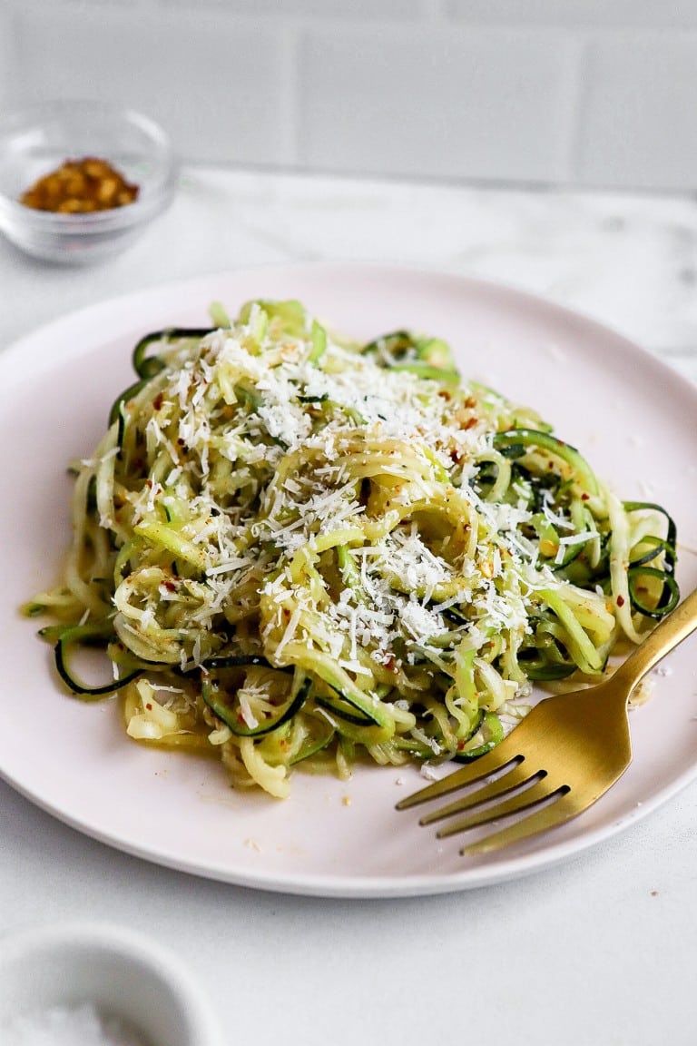 top down view of healthy zucchini noodle recipe with fresh parmesan cheese