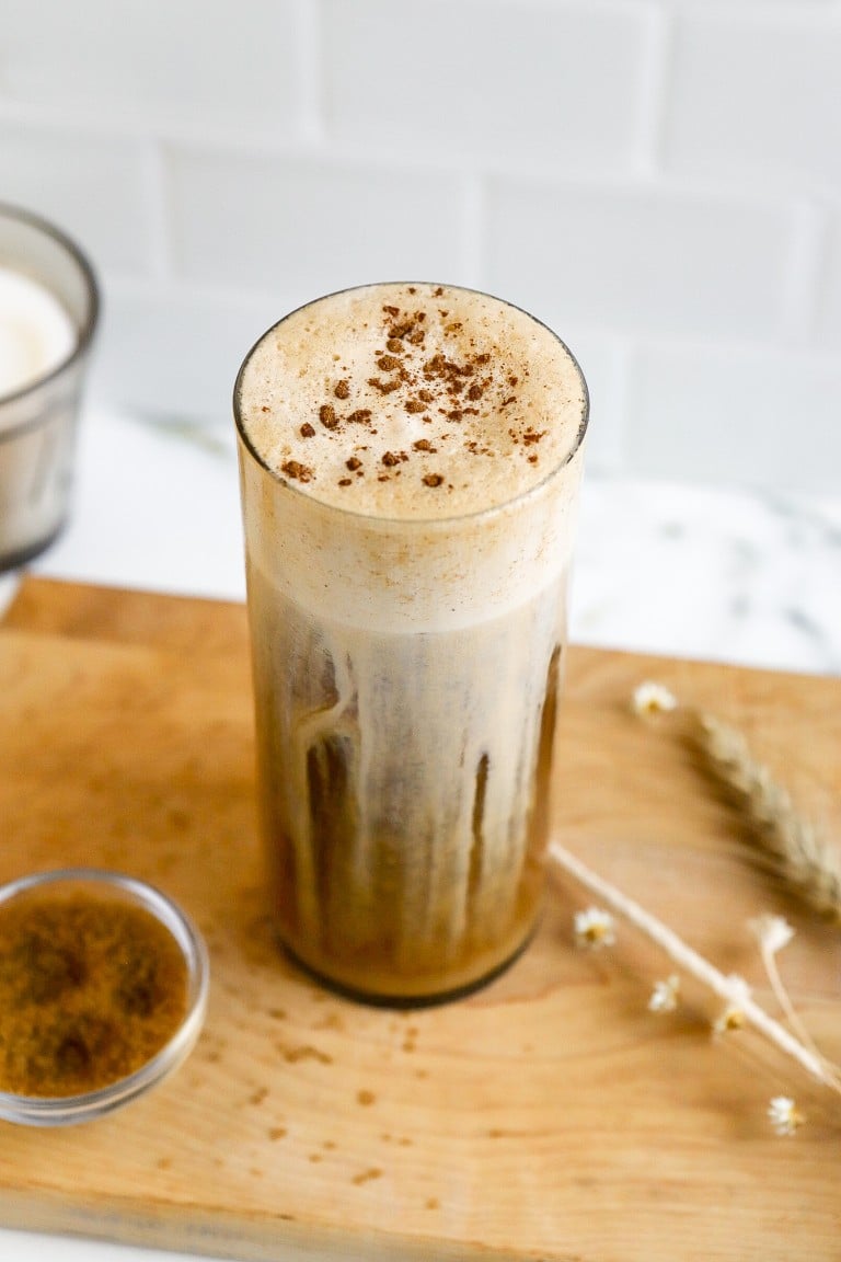 side view of cold coffee in glass with pumpkin spice topping and cinnamon