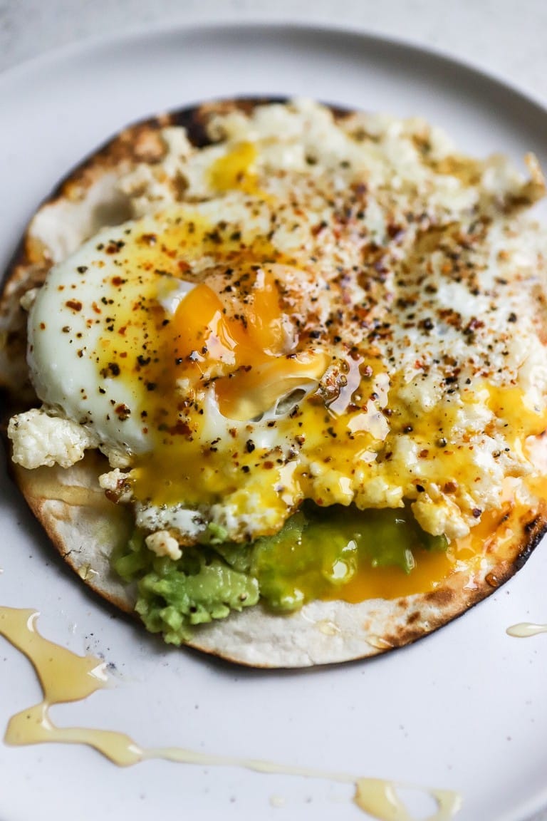 side angle of crispy fried eggs on flour tortilla with yolk popped