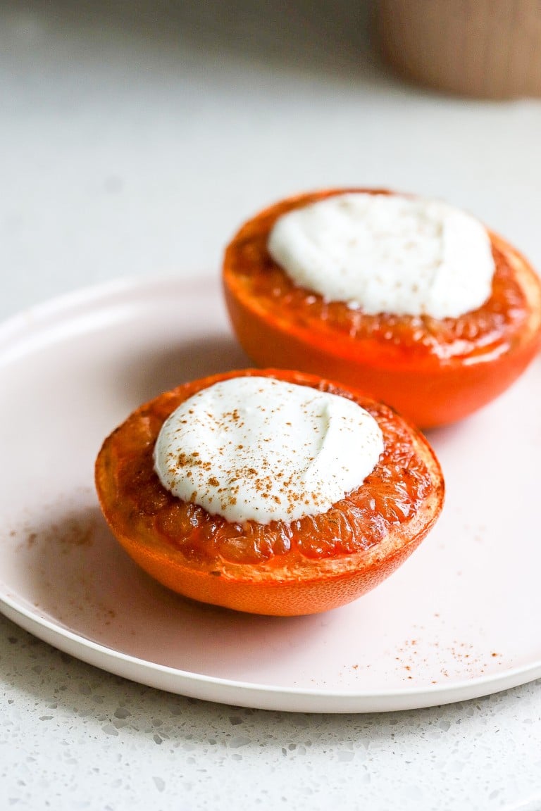 side angle of broiled grapefruit cut in half with greek yogurt on top