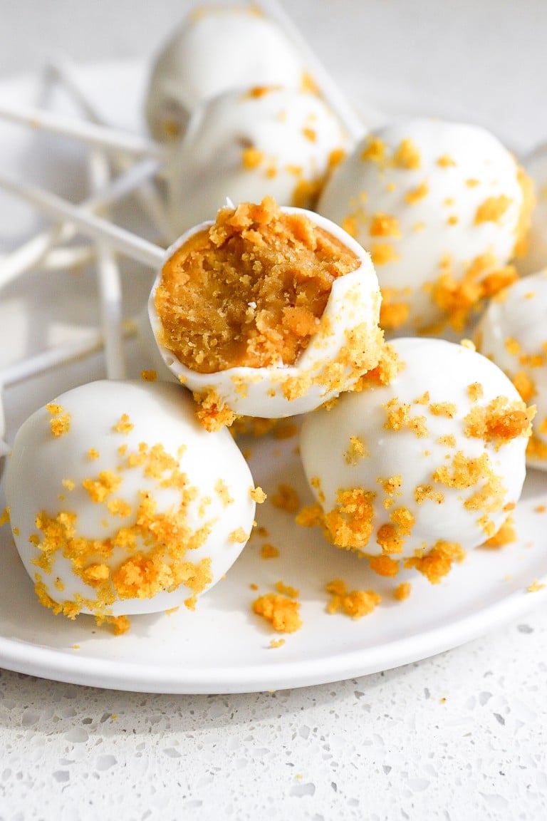 close up shot of festive pumpkin cake pops on white plate