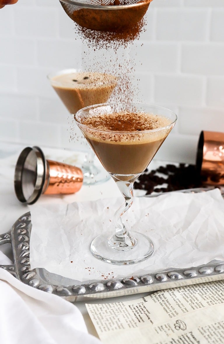 side shot of creamy espresso martini in martini glass with coffee beans in background