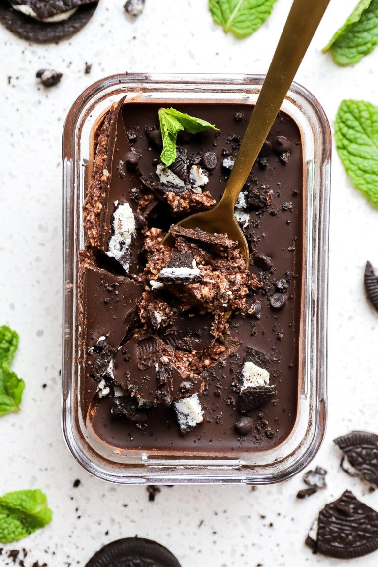 top down view of gold spoon cracked into dark chocolate mint oats with fresh mint