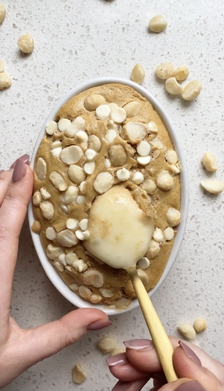 top down view of gold spoon in baked oats with pudding coming out of middle