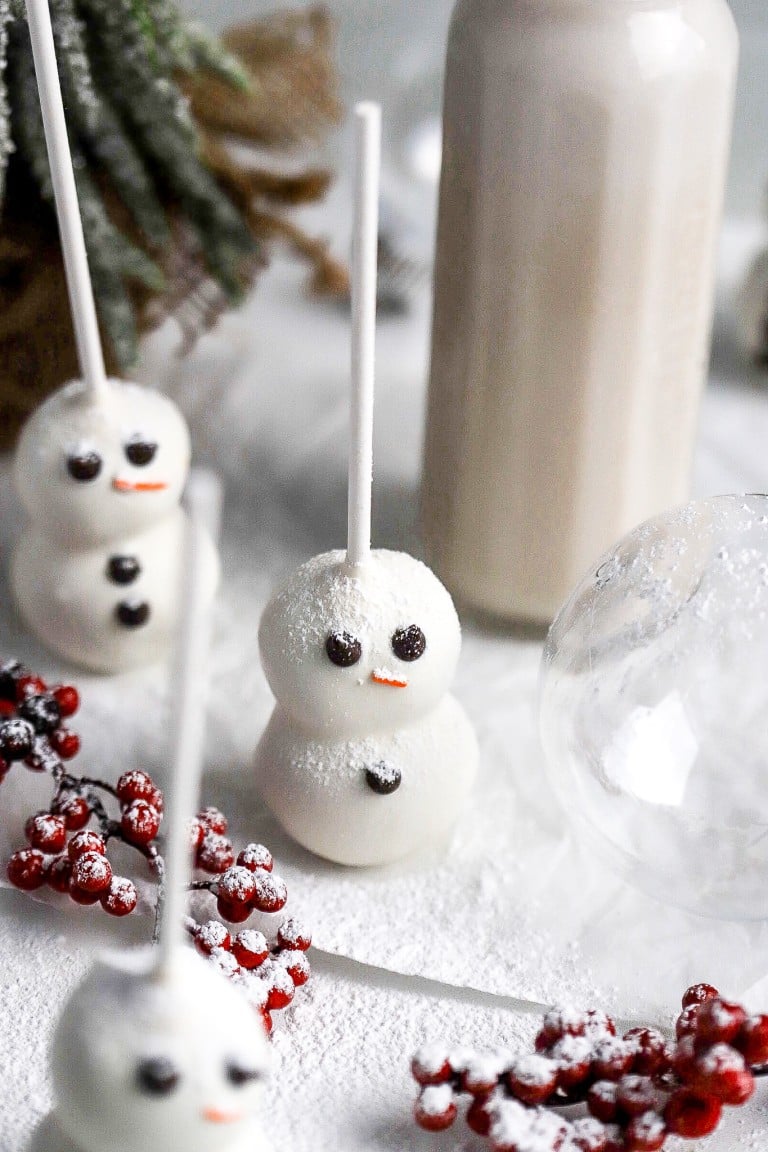 top down view of adorable snowman cake pops with glass of milk in background