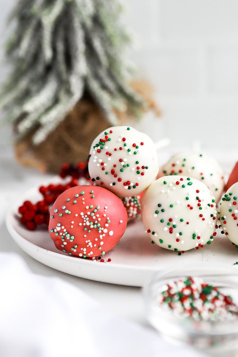 front view of christmas cake pops recipe with sprinkles and christmas tree in background