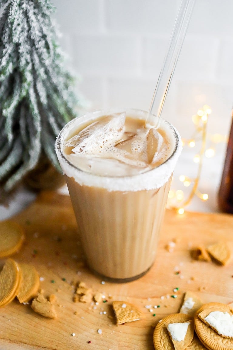 top down view of an iced sugar cookie almondmilk latte in a glass with lights in background