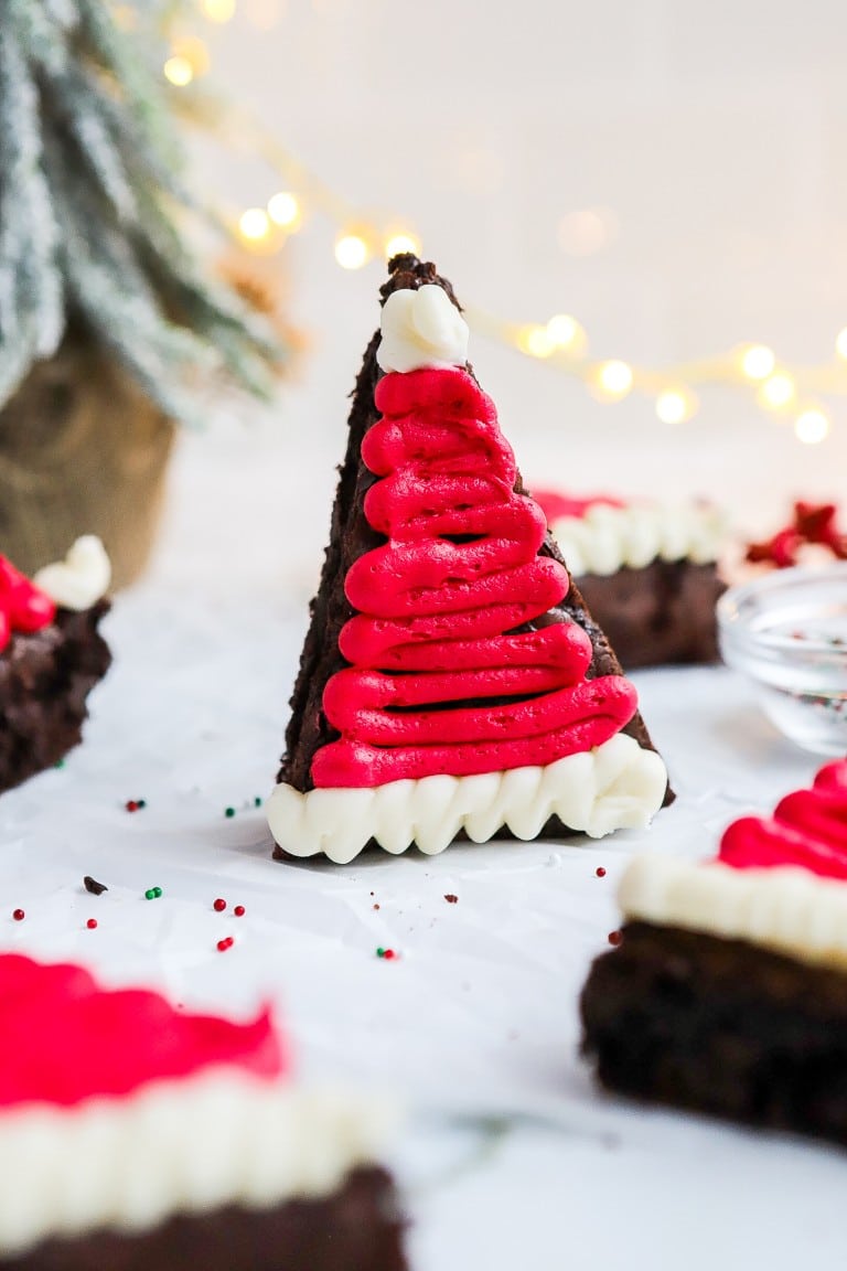 front facing view of triangle brownies decorated with red and white frosting to make a santa hat