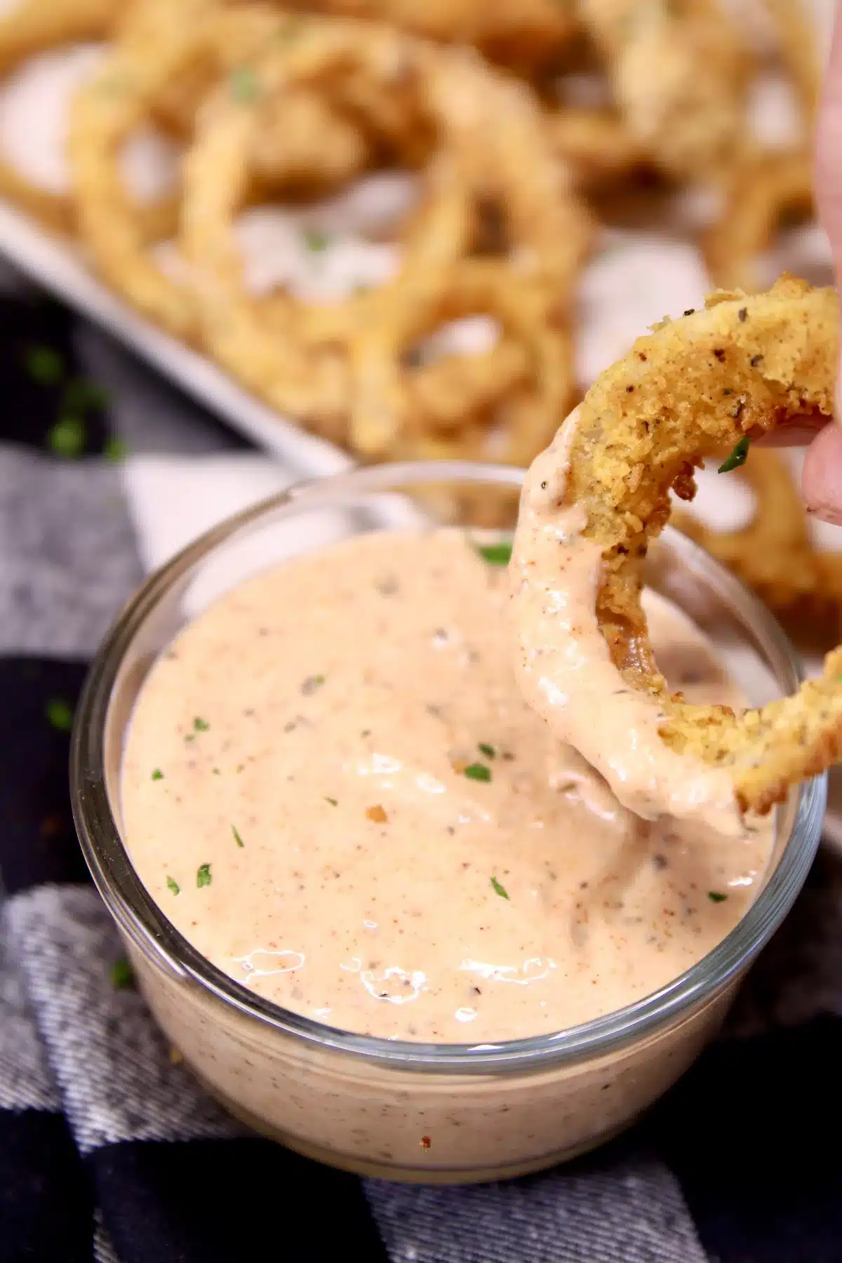 dipping onion ring into blooming onion sauce 