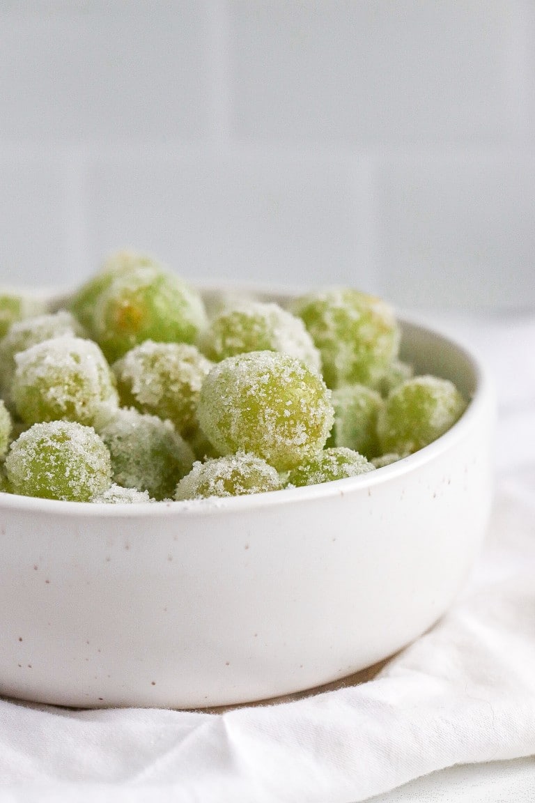 side view of boozy grapes covered in granulated sugar in white bowl