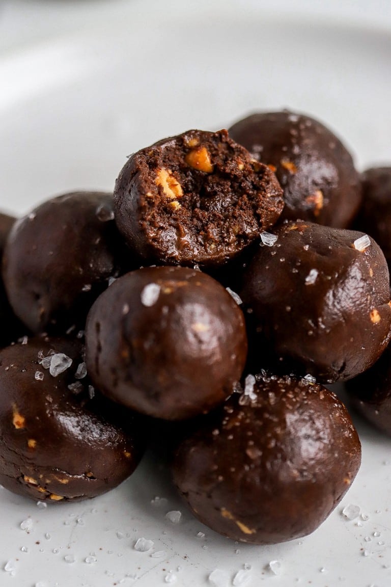 multiple chocolate sea salt protein balls stacked on eachother on white plate