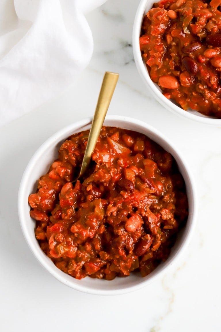 top down view of wendy's chili recipe in a white bowl with gold spoon