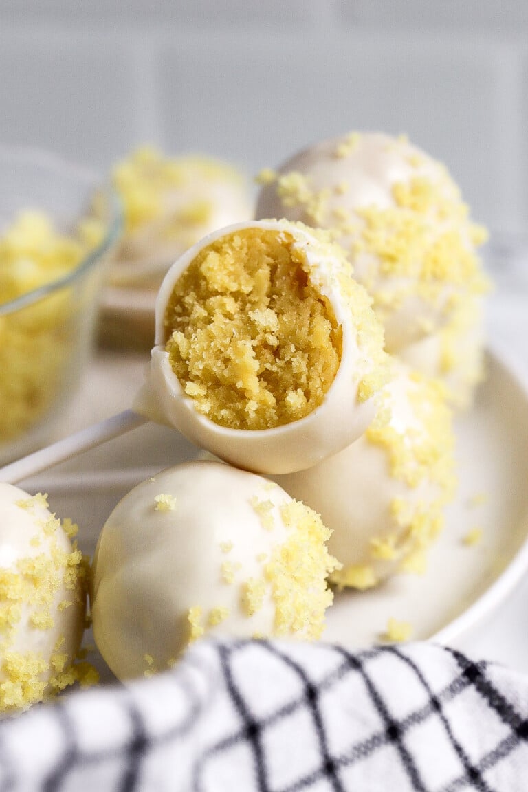 close up shot of lemon cake pops on white plate with blue linen in foreground