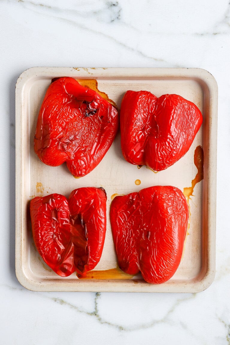 top down shot of 4 roasted red peppers on a air fryer tray