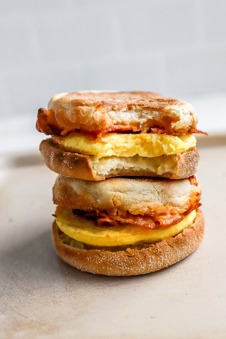 bite shot of 2 breakfast sandwiches stacked on top of each other with bacon and egg