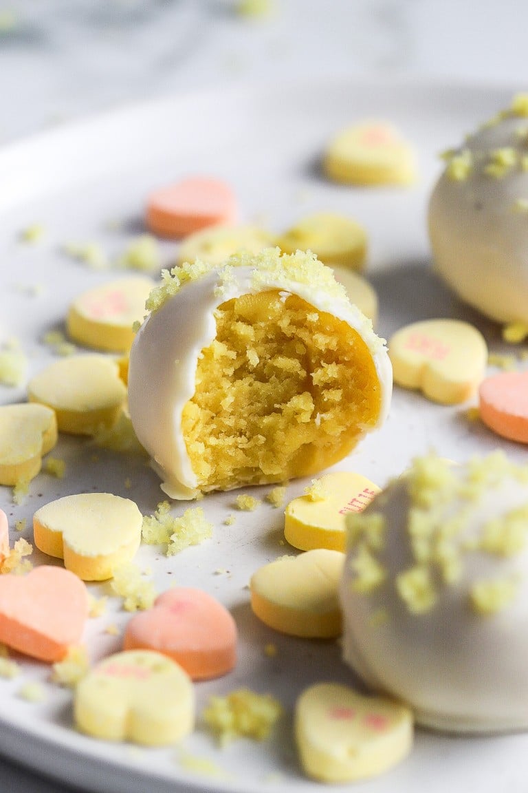 side view of lemon cake balls with white candy coating and cake crumbles on top