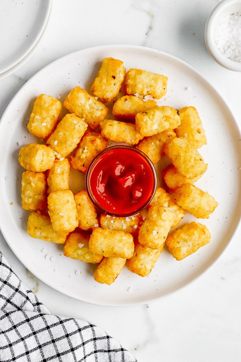 top down view of white plate full of tater tots with ketchup in the middle