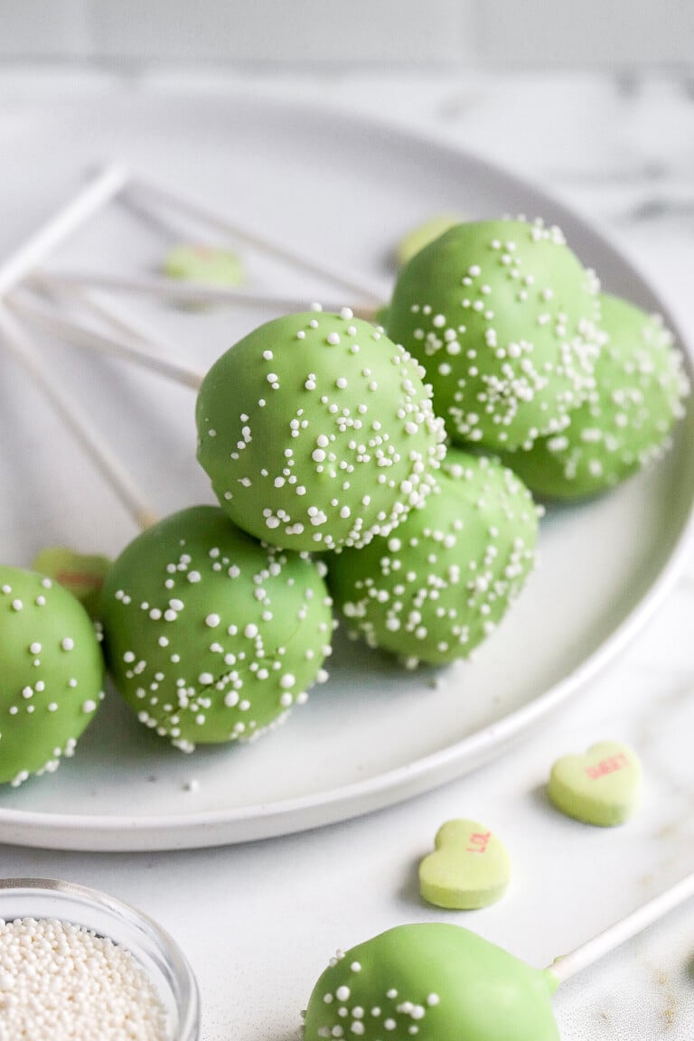 side view of st. Patricks day cake pops on white plate with white sprinkles