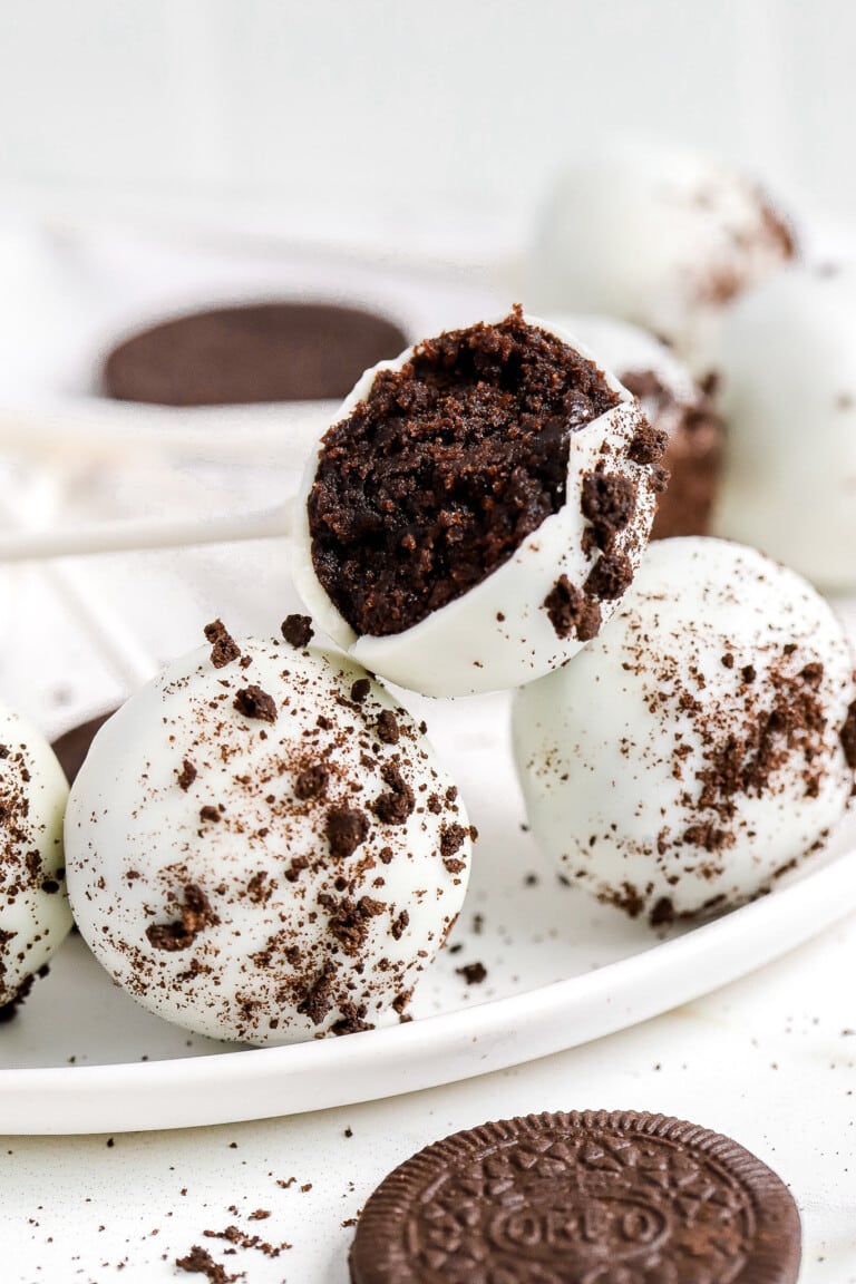 side view of Starbucks cookies and cream cake pops laying on white plate with Oreos