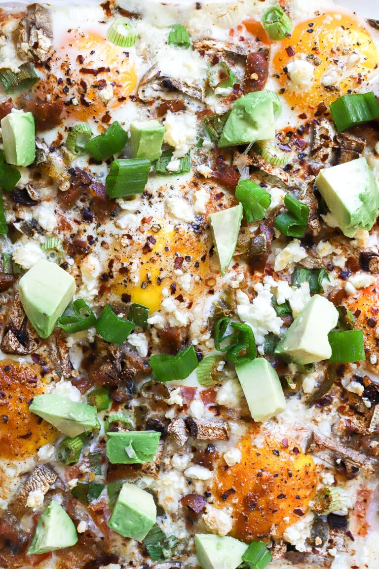 Top down view of air fryer egg frittata with fresh avocado slices and green onions.