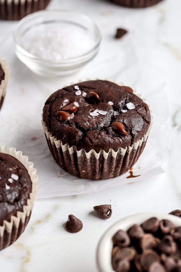 side angle of gluten free double chocolate muffins with sea salt in background on on top of muffins