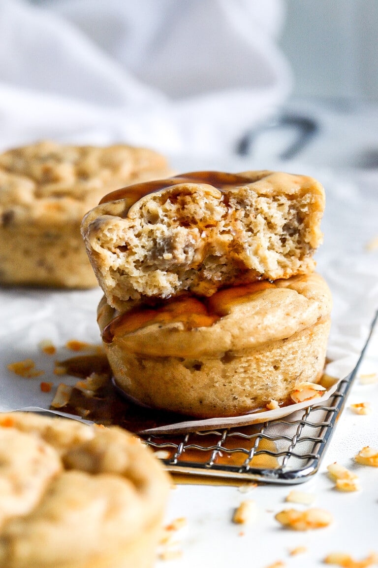 side view of maple flavoured pancakes in muffin form stacked on top of each other with maple syrup