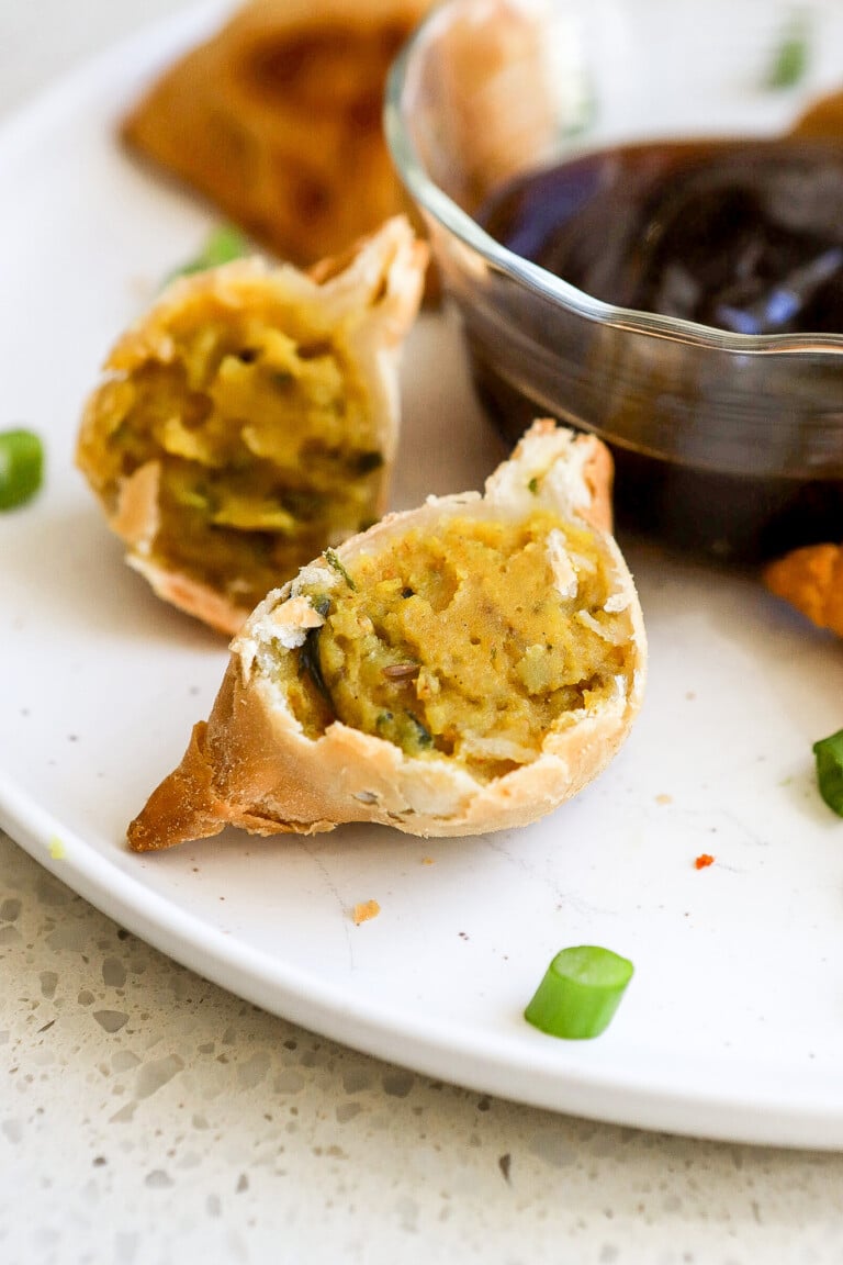 Close up of easy samosas on white plate with dipping sauce in background.